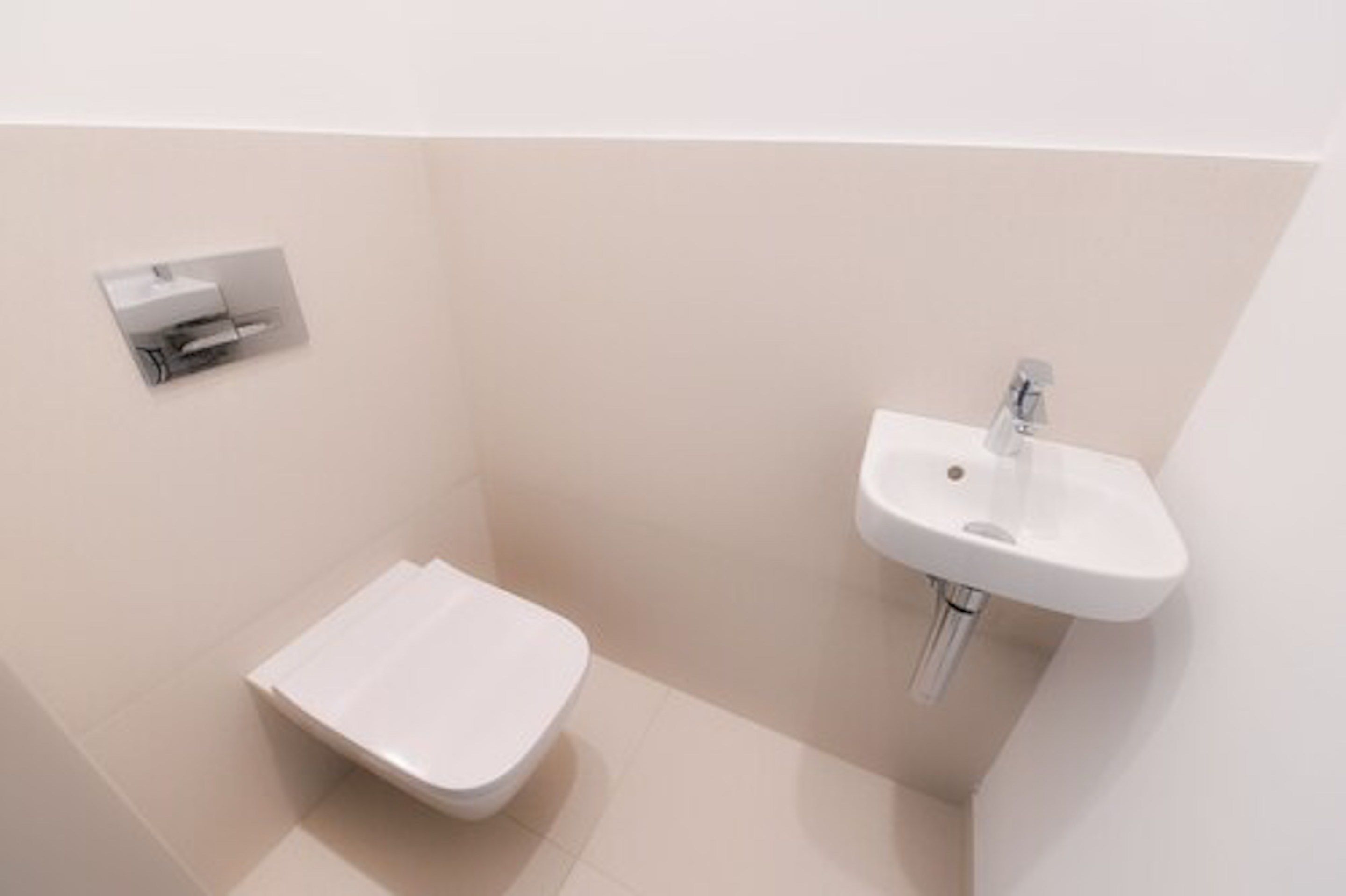 Uma casa de banho moderna com sanita branca, lavatório e dispensador de toalhas.