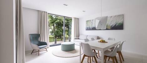 Un comedor moderno con una mesa blanca, sillas y un reposapiés azul.