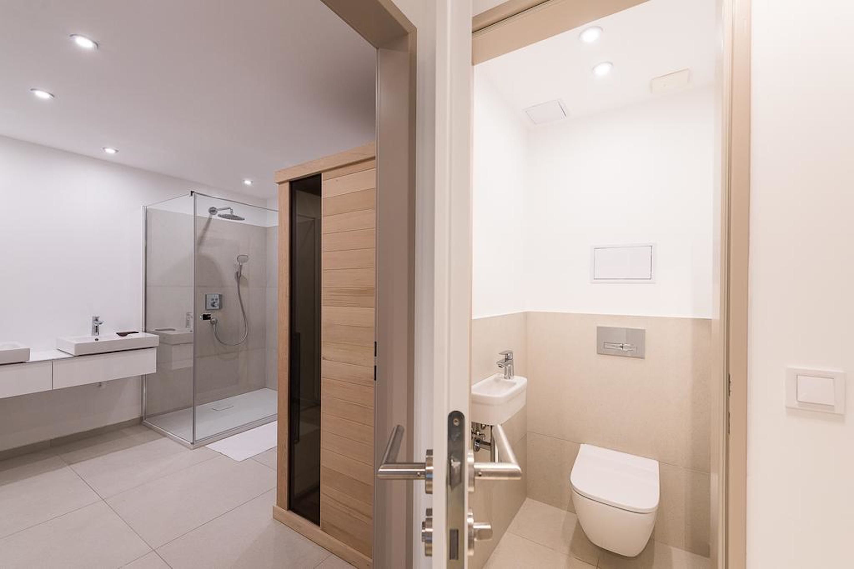 Une salle de bain moderne dotée d’une douche à parois de verre, de toilettes séparées et d’un meuble-lavabo.