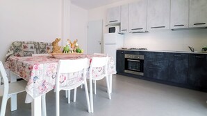 A modern kitchen with white cabinets, a microwave, and a stove. There is a dining table with chairs and a decorative centerpiece.