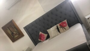 A bed with a tufted headboard, two pillows, and a nightstand. - IV Verdana Rental (Puñal)