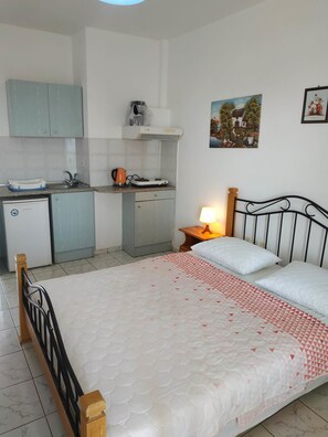 Una habitación compacta con cama, mesita de noche y una pequeña zona de kitchenette.