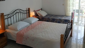 Quarto com duas camas, uma luminária no teto e janela com cortinas.