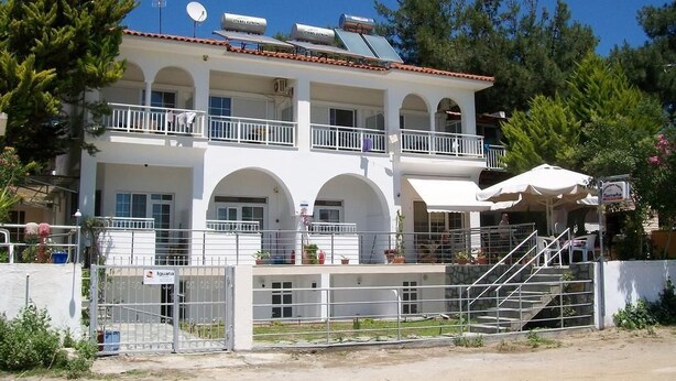 Um edifício de dois andares com fachada branca, várias varandas e uma área de estar coberta ao ar livre.