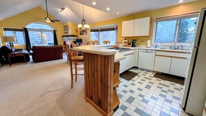 A kitchen with a central island, wooden cabinets, a dining area with a sofa, and large windows.