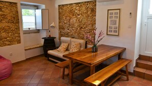 Une pièce chaleureuse avec un mur en pierre, une table en bois avec des bancs, un canapé et une fenêtre donnant sur un beau paysage.
