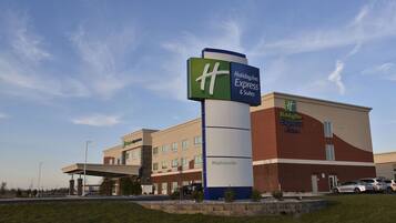 A Holiday Inn Express & Suites building with a prominent sign, a parking lot, and a clear sky.