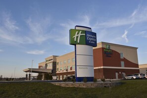 A Holiday Inn Express & Suites building with a prominent sign, a parking lot, and a clear sky. - Holiday Inn Express & Suites Madisonville by IHG (Madisonville)