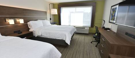 A hotel room with two beds, a desk, a TV, and a large window.