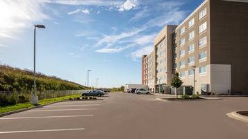 A parking lot with several cars, a building with multiple windows, and a clear sky.