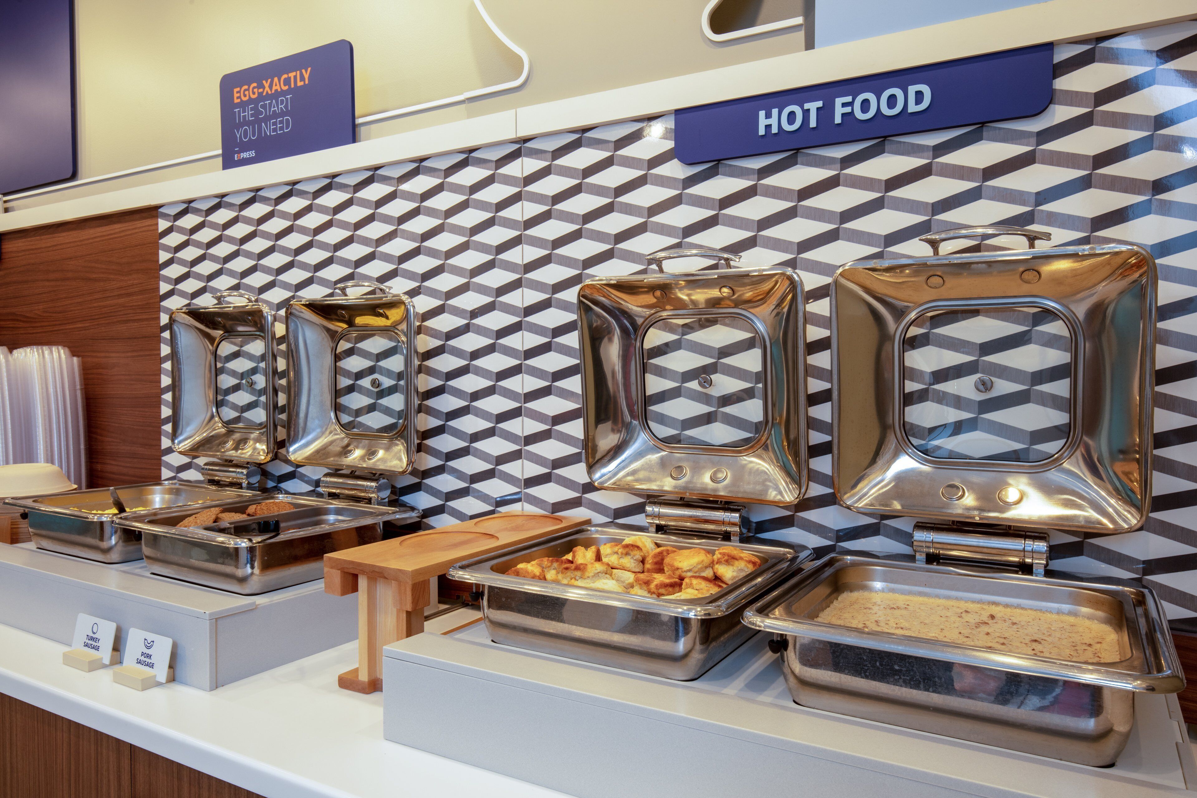 A buffet with various food options, including hot food, and a sign indicating 'EGG-XACTLY THE START YOU NEED'.