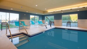An indoor swimming pool with clear blue water, surrounded by windows offering views of greenery and a parking lot. - Holiday Inn Express & Suites Beloit by IHG (Beloit)