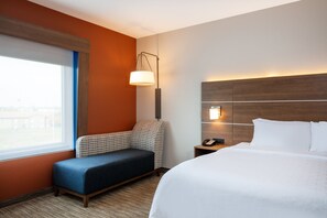 A hotel room with a bed, a seating area, a lamp, and a nightstand. - Holiday Inn Express & Suites Beloit by IHG (Beloit)