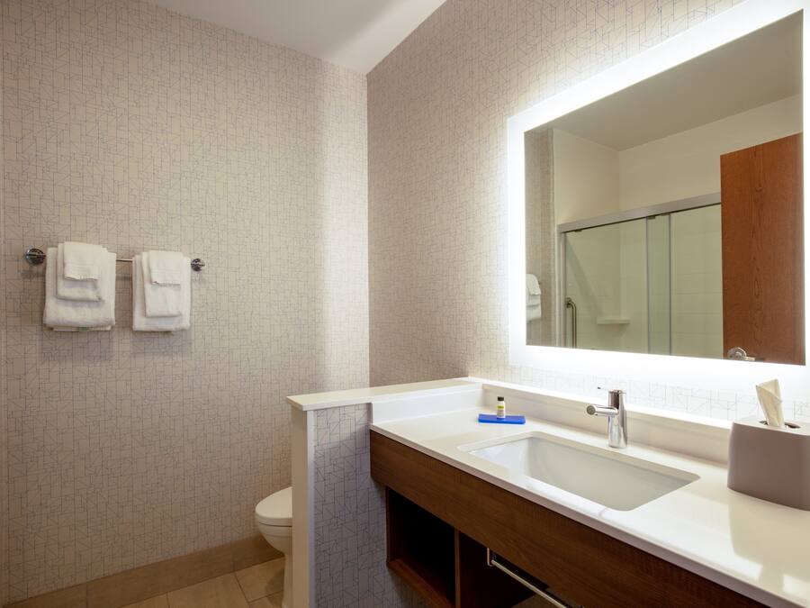 Ein Badezimmer mit einem weißen Waschbecken, einem Spiegel und zwei Handtüchern, die an der Wand hängen.