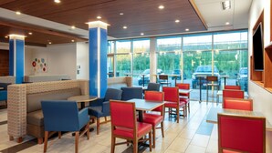 A modern restaurant with booths and tables, large windows with a view of cars and greenery outside. - Holiday Inn Express & Suites Beloit by IHG (Beloit)