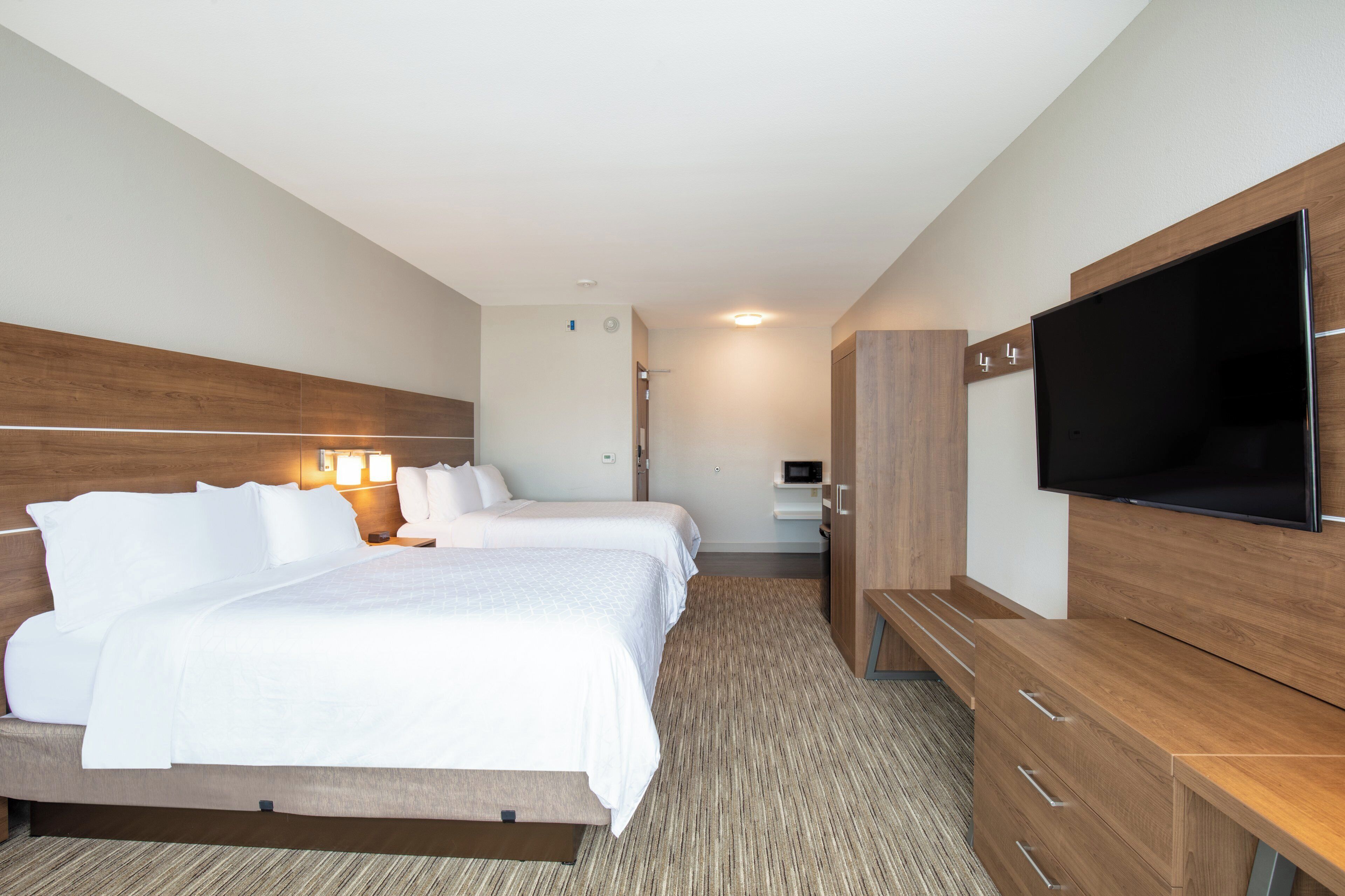 A hotel room with two beds, a TV, a desk, and a wardrobe.