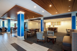 En moderne hotellobby med spiseplads, siddepladser og en receptionsdisk.
