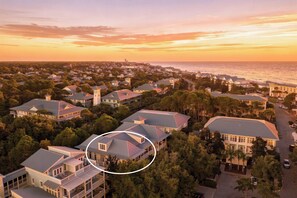 A coastal residential area with houses, a view of the ocean, and a highlighted building with a distinctive roof. - WaterColor Condo‑Retreat | 2.5BR/2BA - Bikes, Balcony, Walk to Beach Club (Santa Rosa Beach)