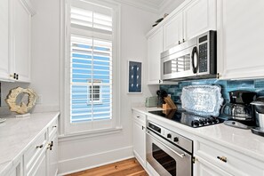 A modern kitchen with white cabinetry, a built-in oven, a microwave, and a coffee maker. - WaterColor Condo‑Retreat | 2.5BR/2BA - Bikes, Balcony, Walk to Beach Club (Santa Rosa Beach)