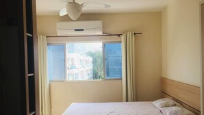 Een slaapkamer met een bed, twee kussens, een plafondventilator en een airconditioning.