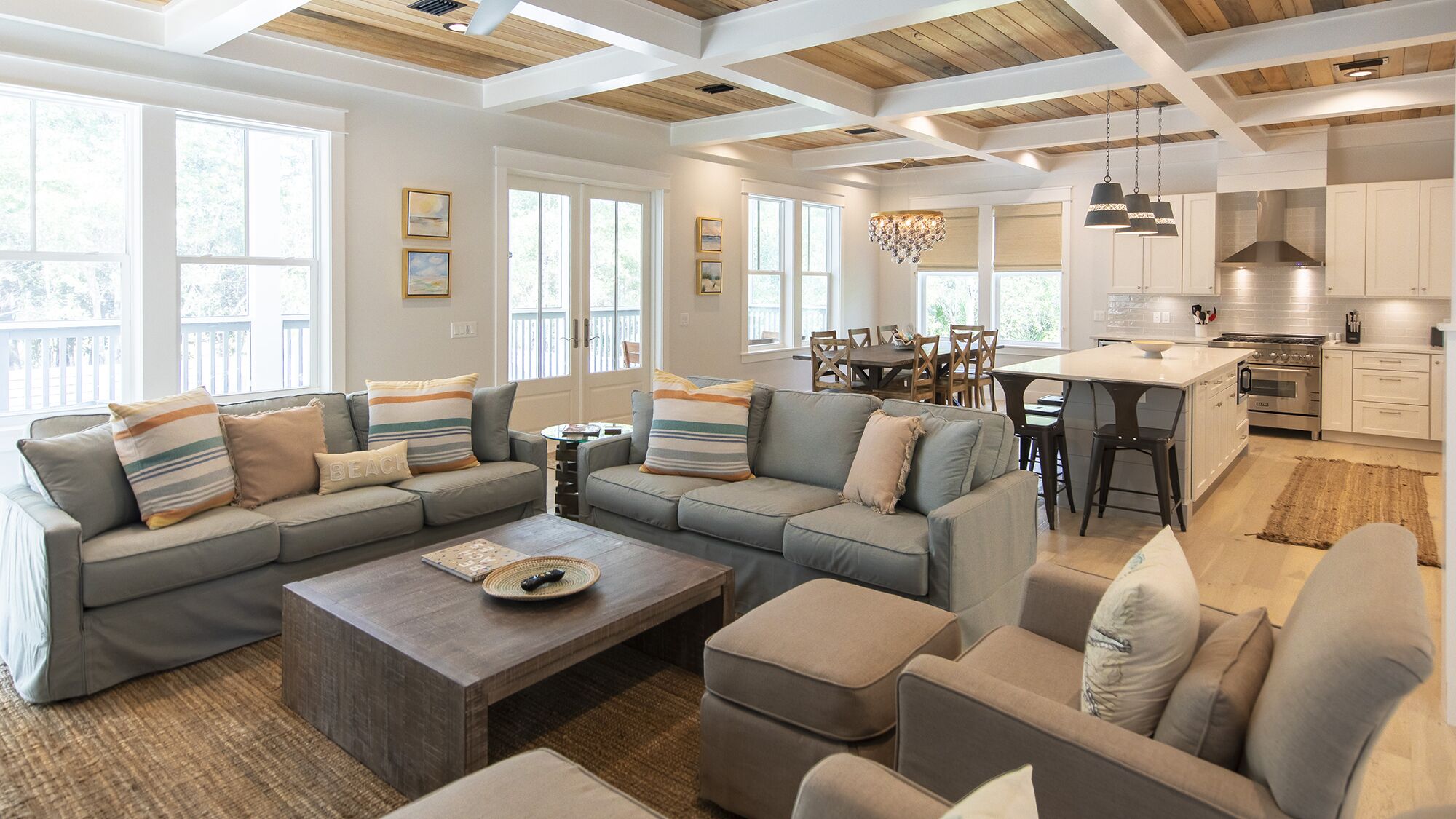 A spacious living room with a sectional sofa, a coffee table, and a dining area with a chandelier.