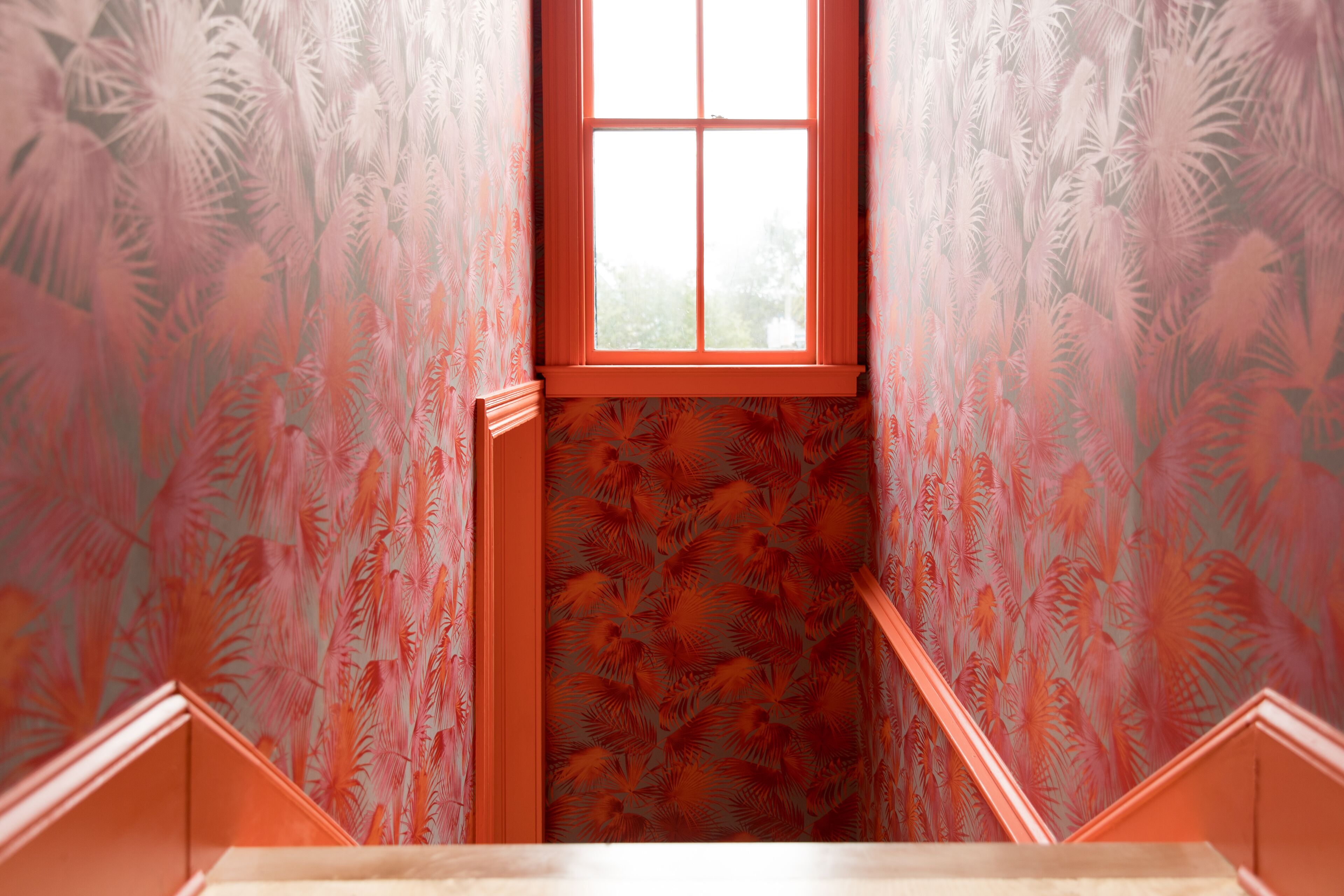 A narrow stairway with a window at the top, leading to a landing.