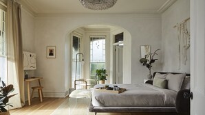 A bedroom with a bed, bedside table, chair, and a view of a balcony. - Dreamers BNB (Wilmington)