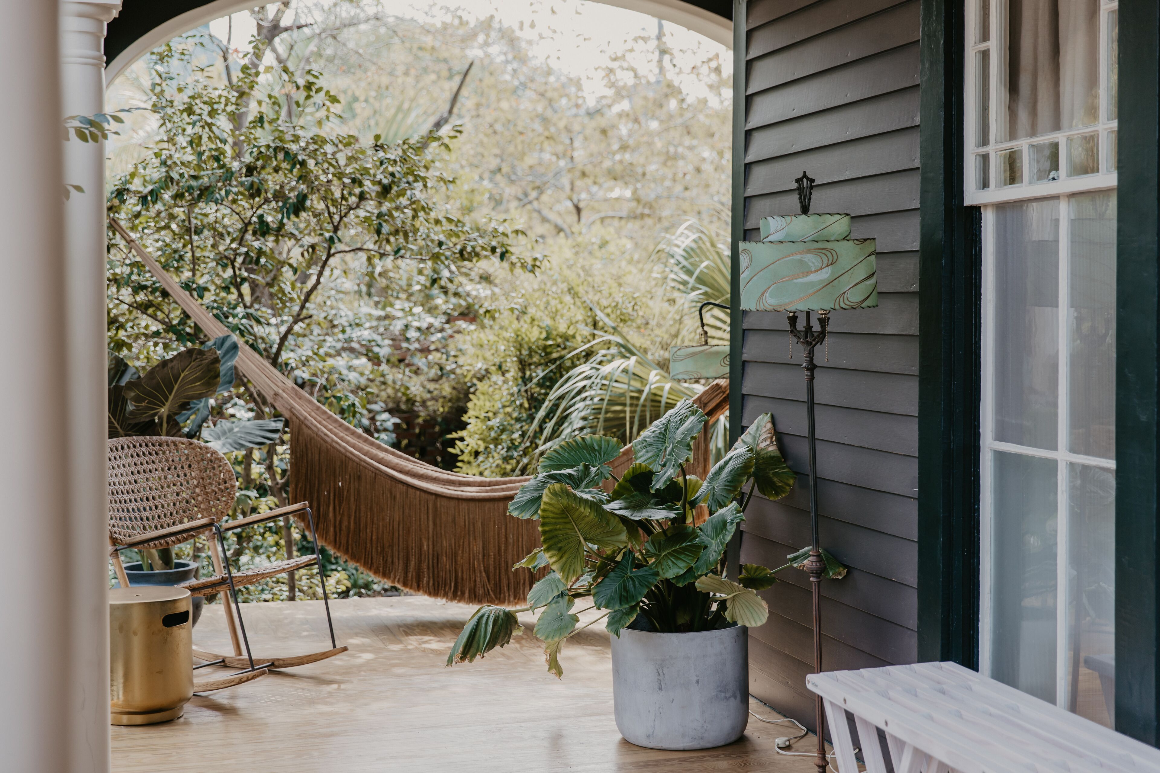 A porch with a hammock, a potted plant, and a bench.