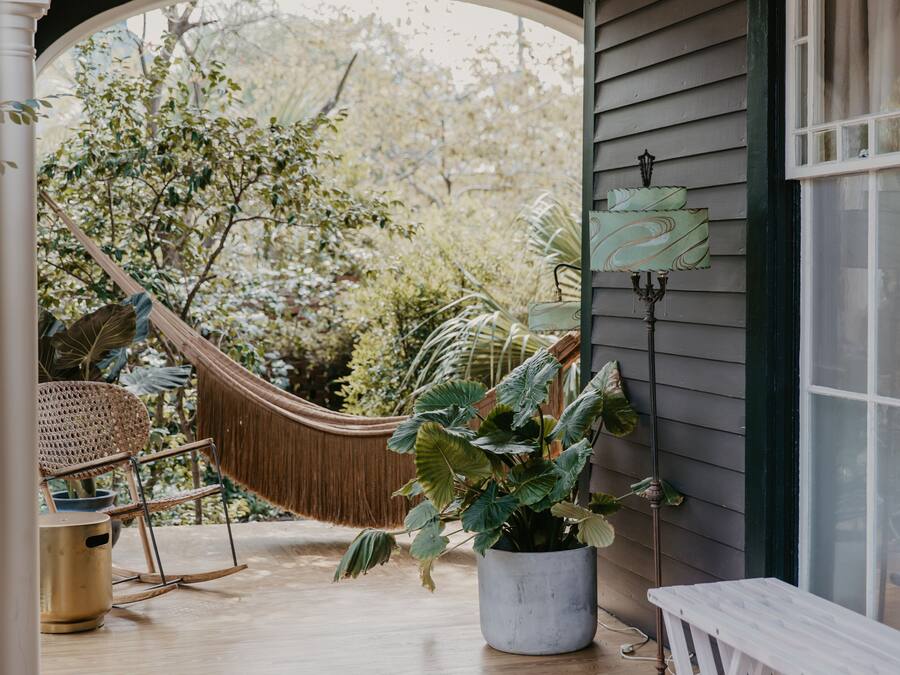 A porch with a hammock, a potted plant, and a bench.
