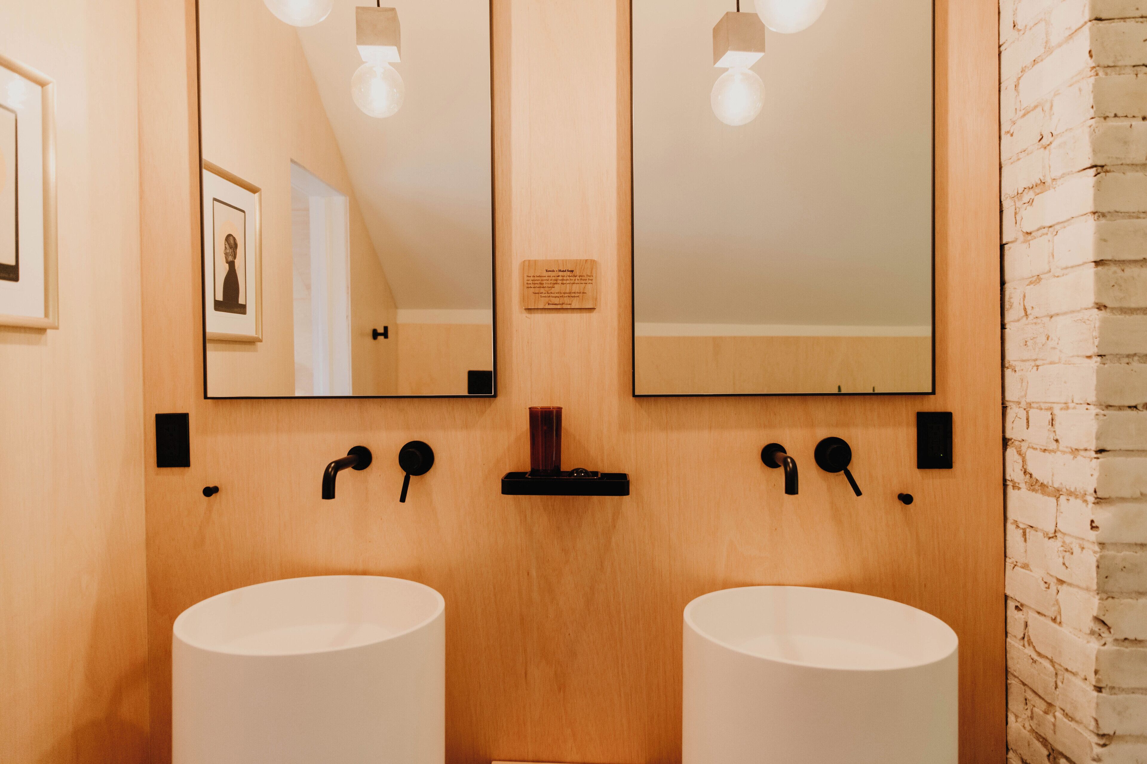 A bathroom with two white sinks, wooden wall panels, and a mirror above.