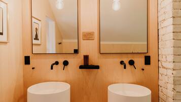 A bathroom with two white sinks, wooden wall panels, and a mirror above.