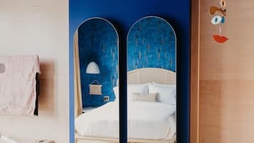 A bedroom with a bed, a nightstand, a lamp, and a wall-mounted mirror.