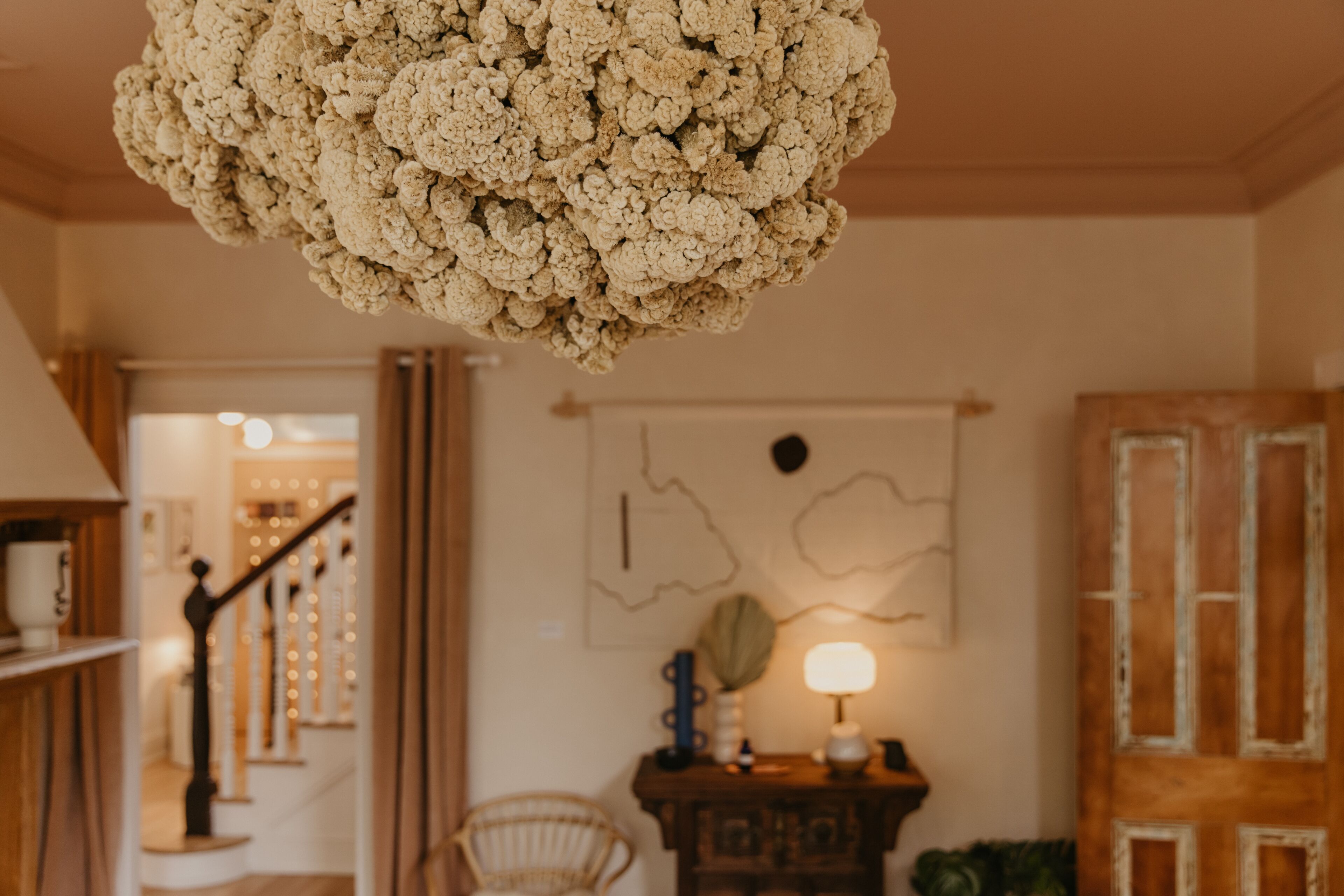 A room with a textured ceiling light fixture, a staircase, a chair, a wooden cabinet, and a door with a rustic finish.