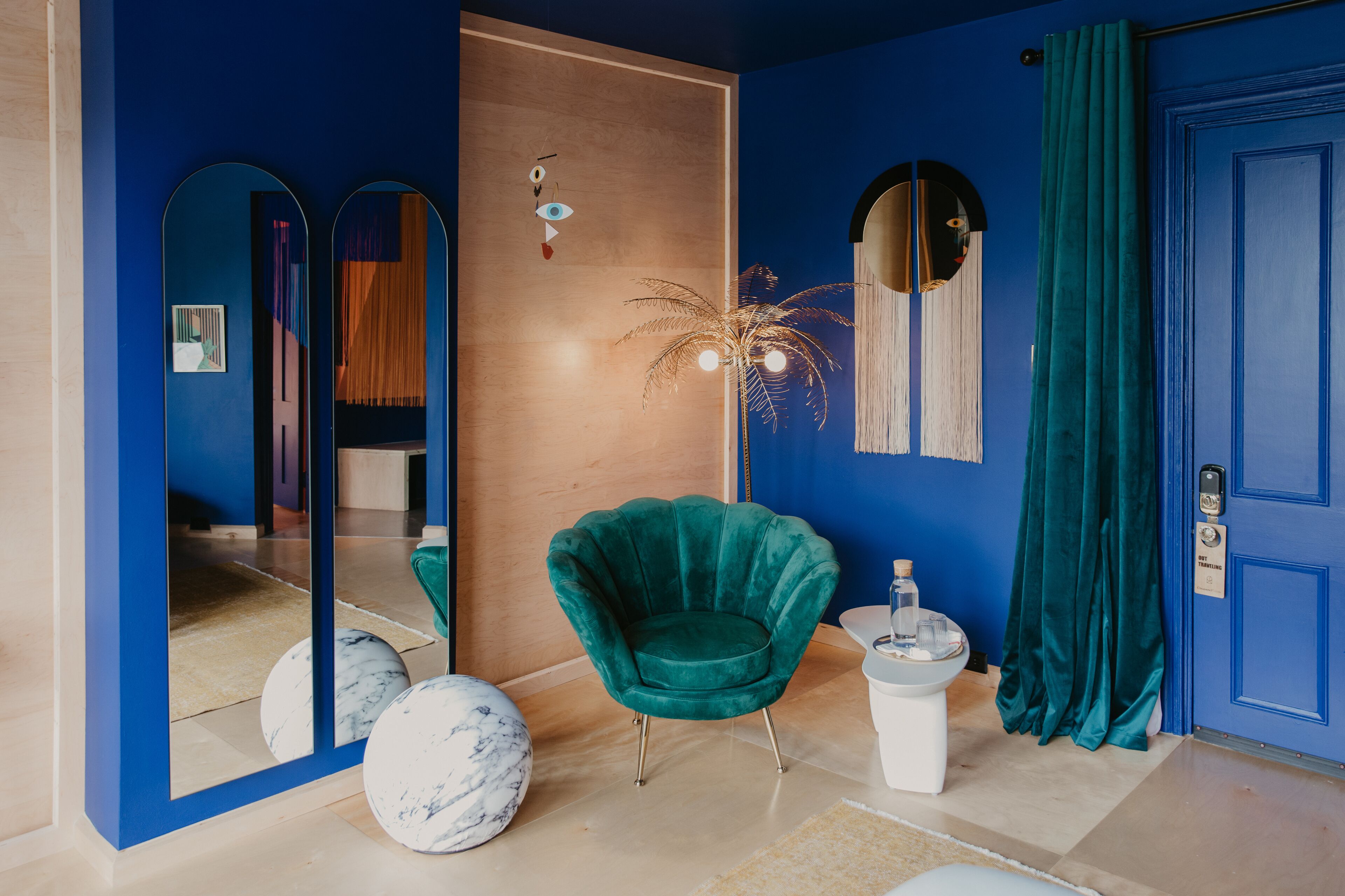 Ein Zimmer mit einem türkisfarbenen Sessel, einem weißen Podest und einer blauen Tür.