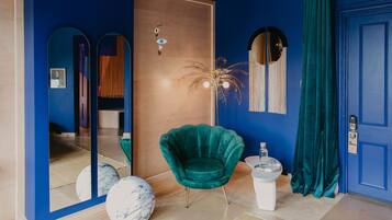 Ein Zimmer mit einem türkisfarbenen Sessel, einem weißen Podest und einer blauen Tür.