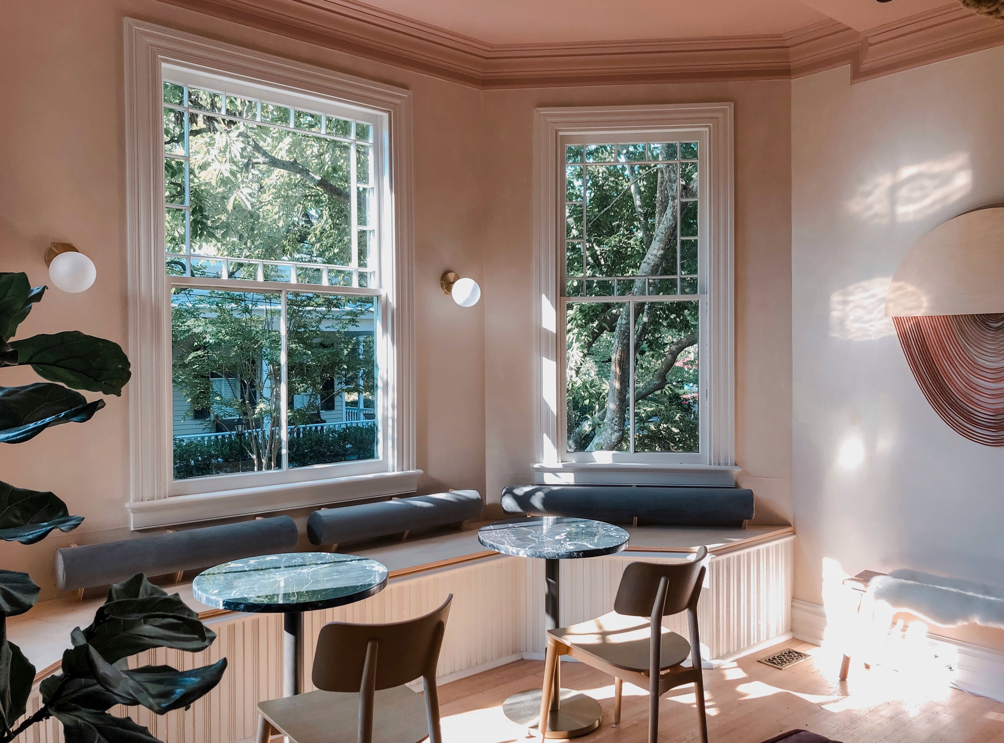 Una habitación soleada con ventanas amplias, un radiador, una mesa redonda y dos sillas.