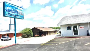 A parking lot with a sign for Lakeside Inn, a building with an office sign, and a vehicle in the distance. - Lakeside inn (Eufaula)