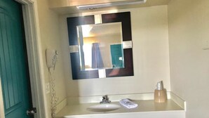 A bathroom with a white sink, a mirror, and a towel dispenser. - Lakeside inn (Eufaula)