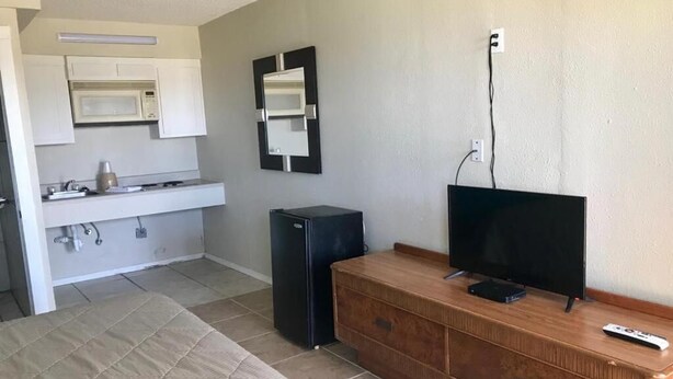 A compact living space with a kitchenette, a television, and a small refrigerator. - Lakeside inn (Eufaula)