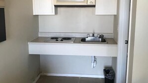 A compact kitchen with a microwave, stove, sink, and tiled floor. - Lakeside inn (Eufaula)