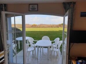 A room with a glass door leading to an outdoor patio with a table and chairs.