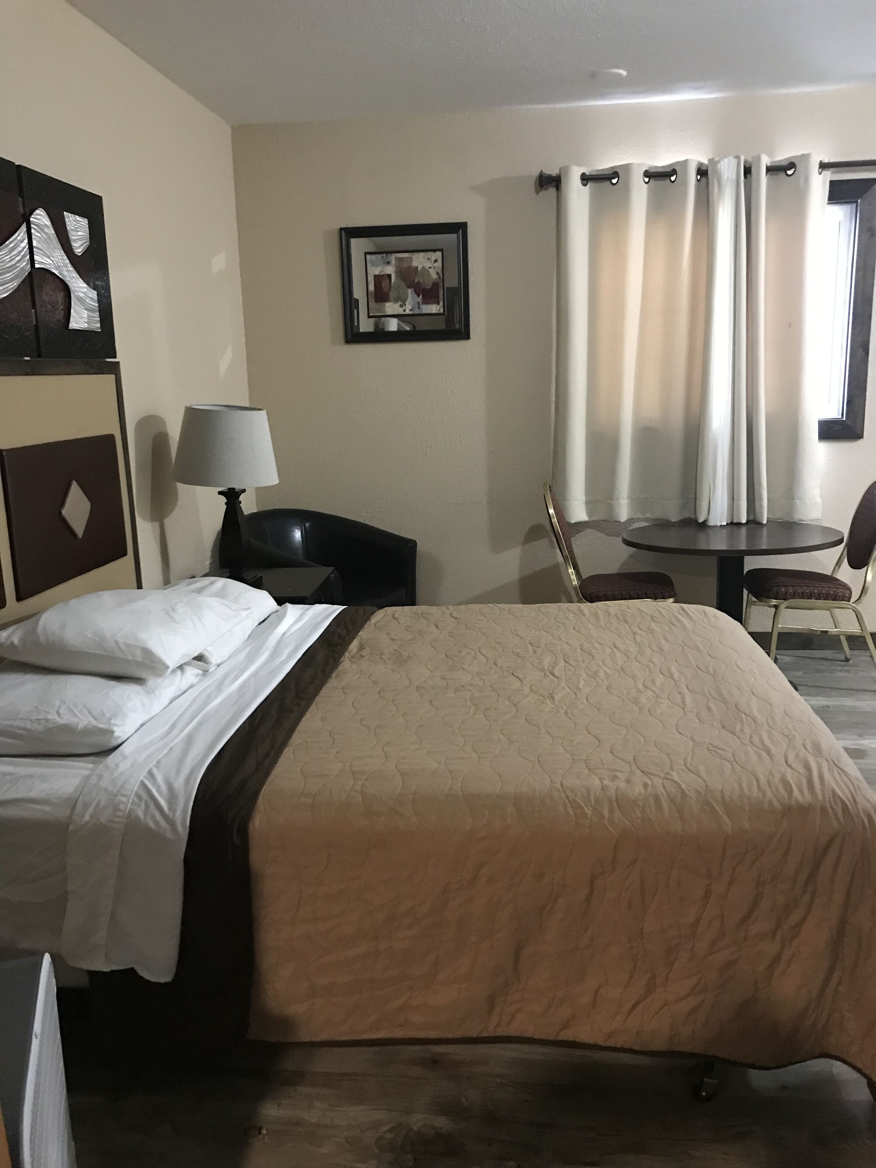 Ein Hotelzimmer mit Bett, Schreibtisch, Stuhl, Lampe und einem Bild an der Wand.