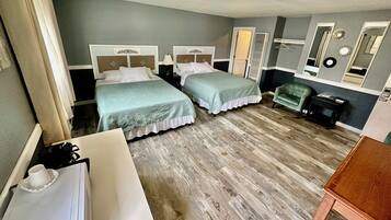 A hotel room with two beds, a desk, a chair, and a mirror.