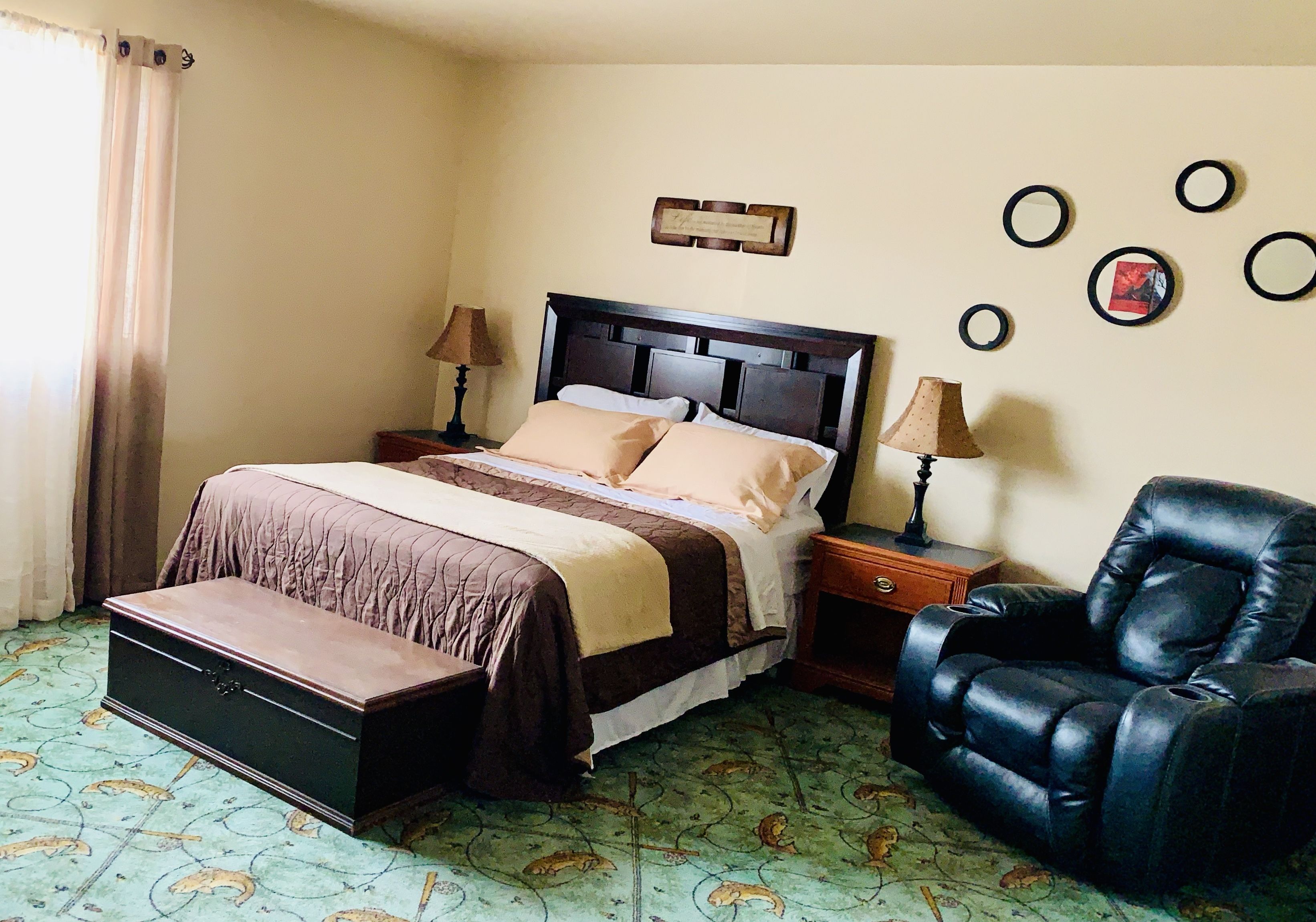 A neatly arranged hotel room with a bed, bedside tables, a chair, and a decorative wall piece.