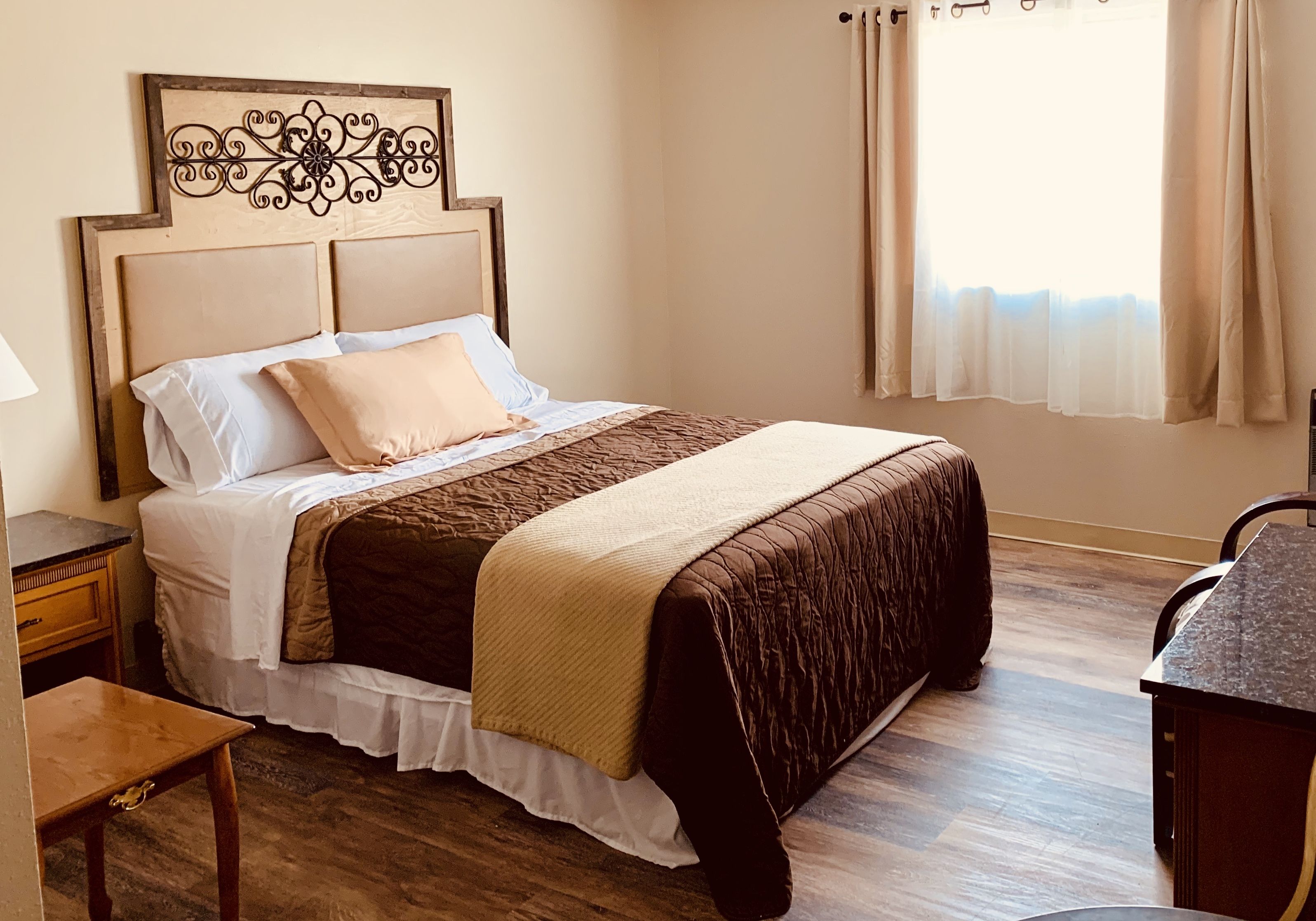 A neatly arranged bedroom with a bed, bedside table, and a desk.