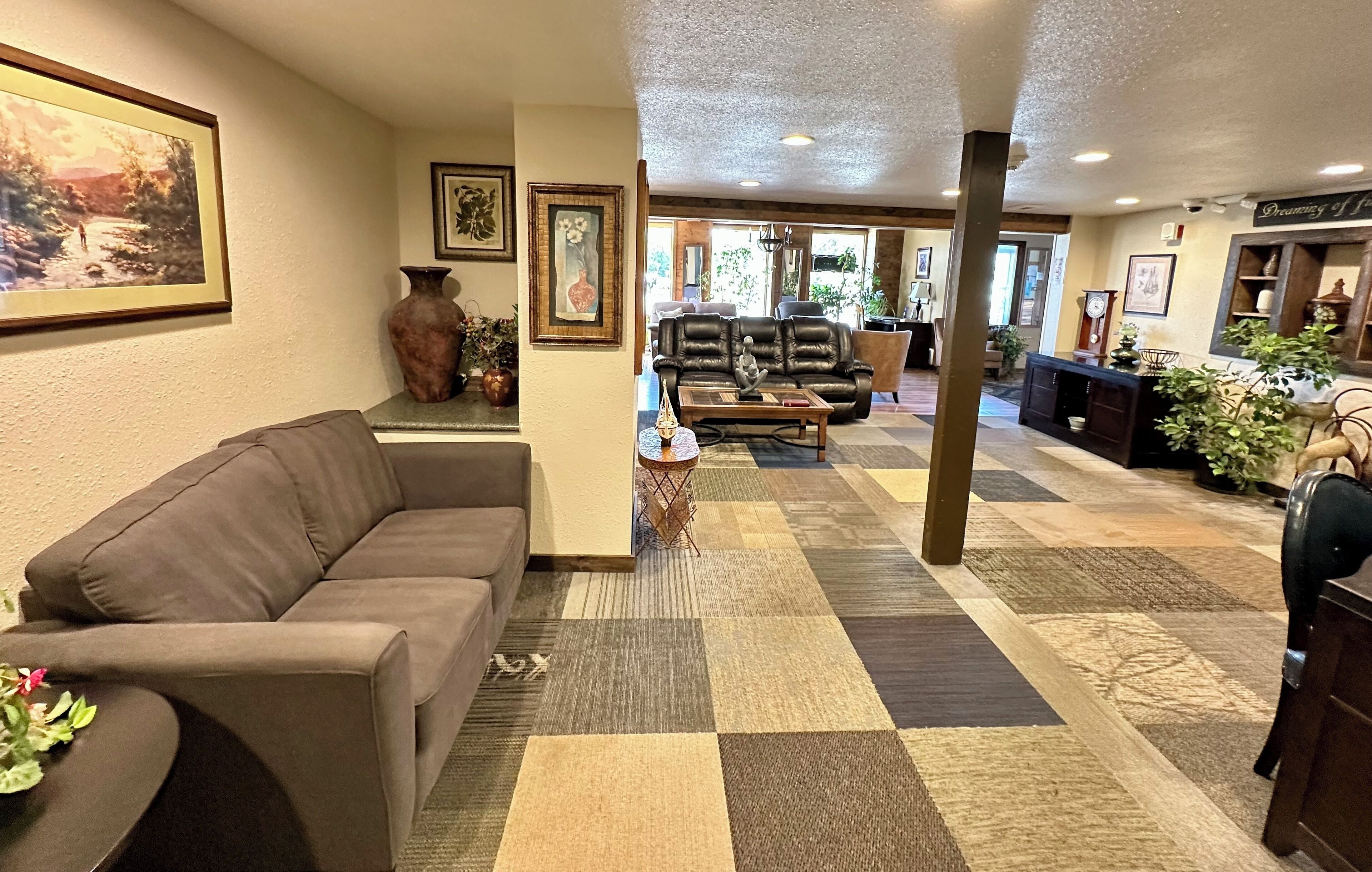 A spacious lobby with a large sofa, a coffee table, and a patterned carpet.