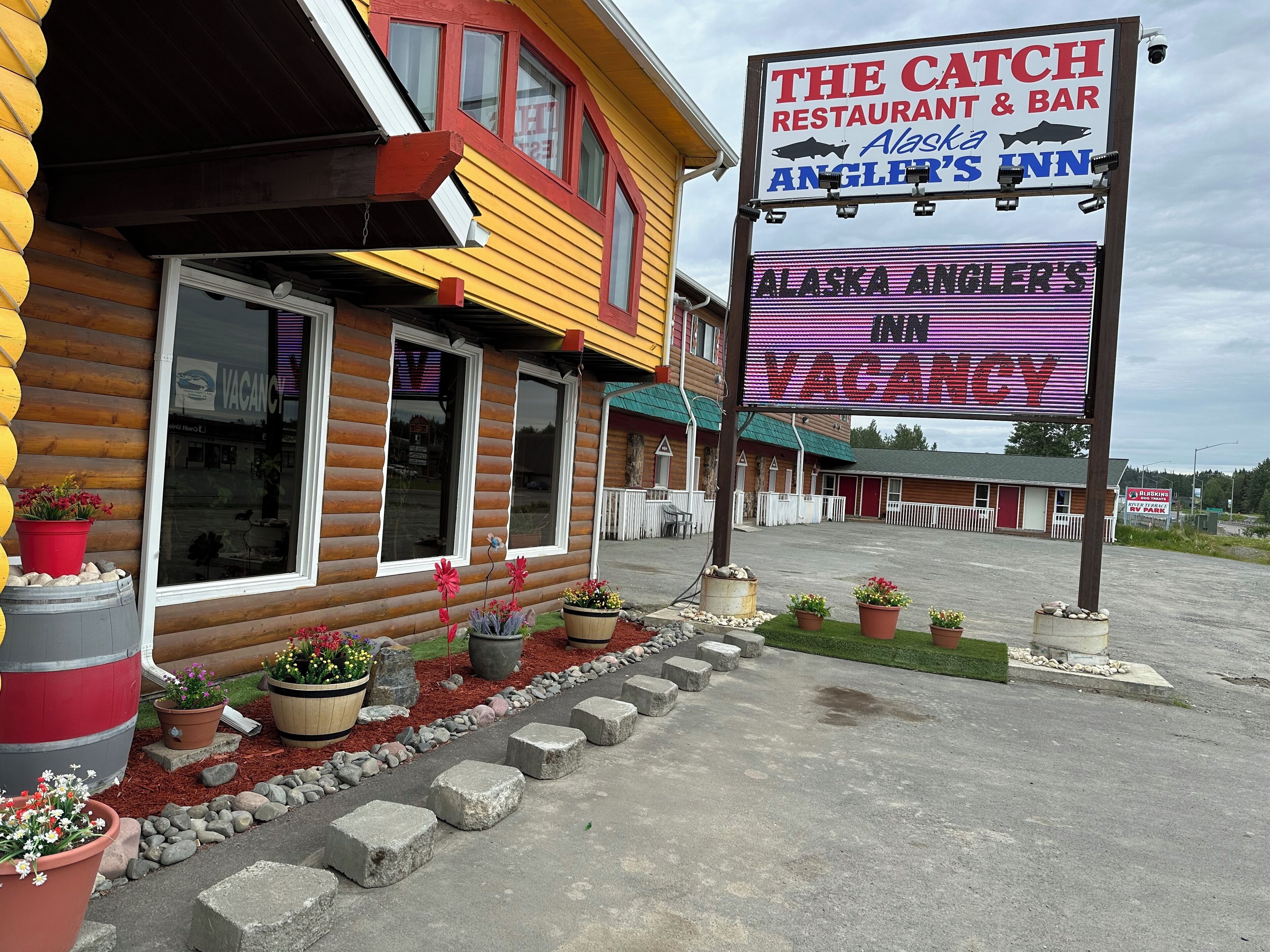A wooden building with a sign indicating 'The Catch Restaurant & Bar' and 'Alaska Angler's Inn'.