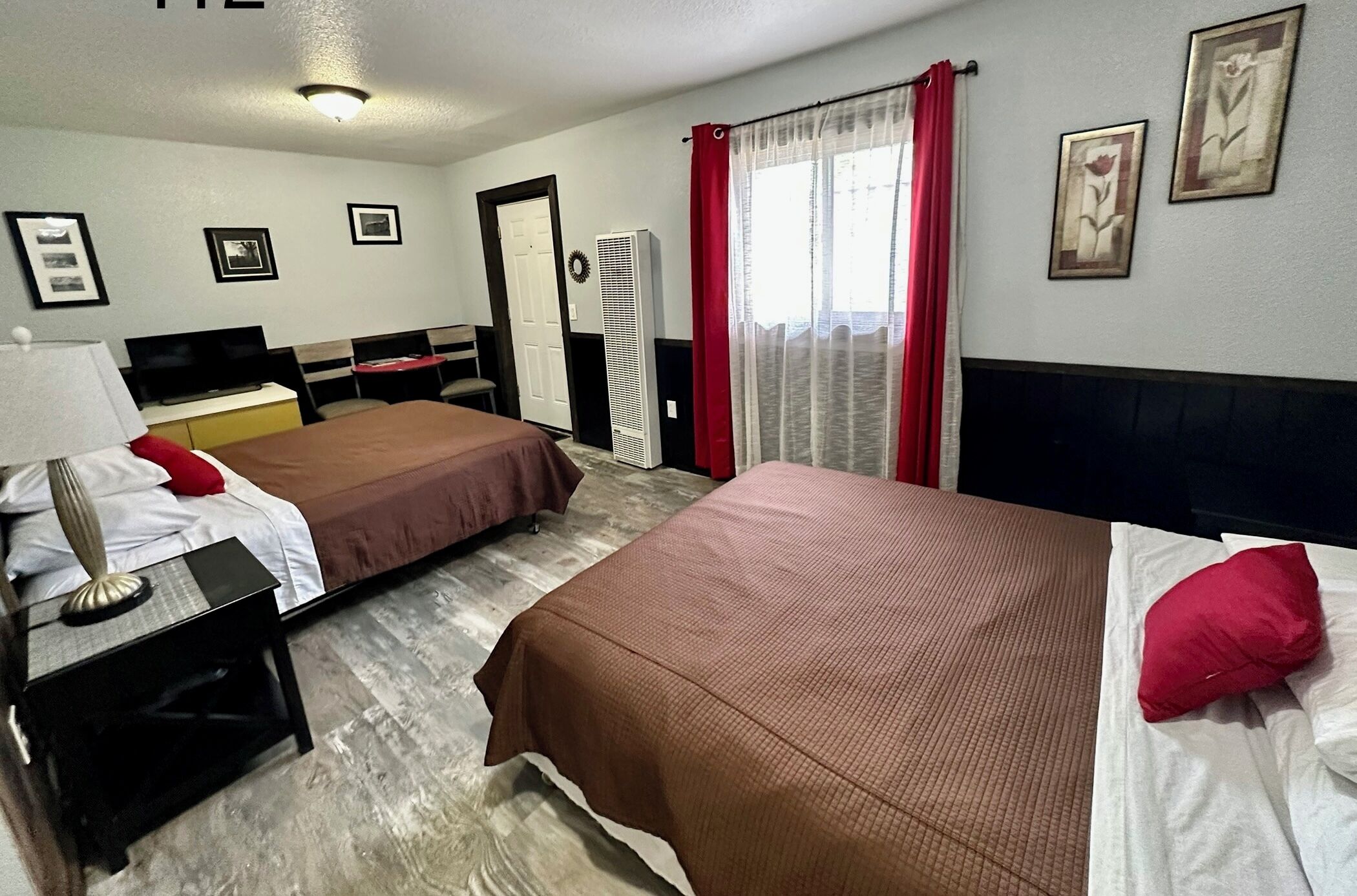 Habitación de hotel con dos camas, un escritorio, una silla, un televisor y un armario.
