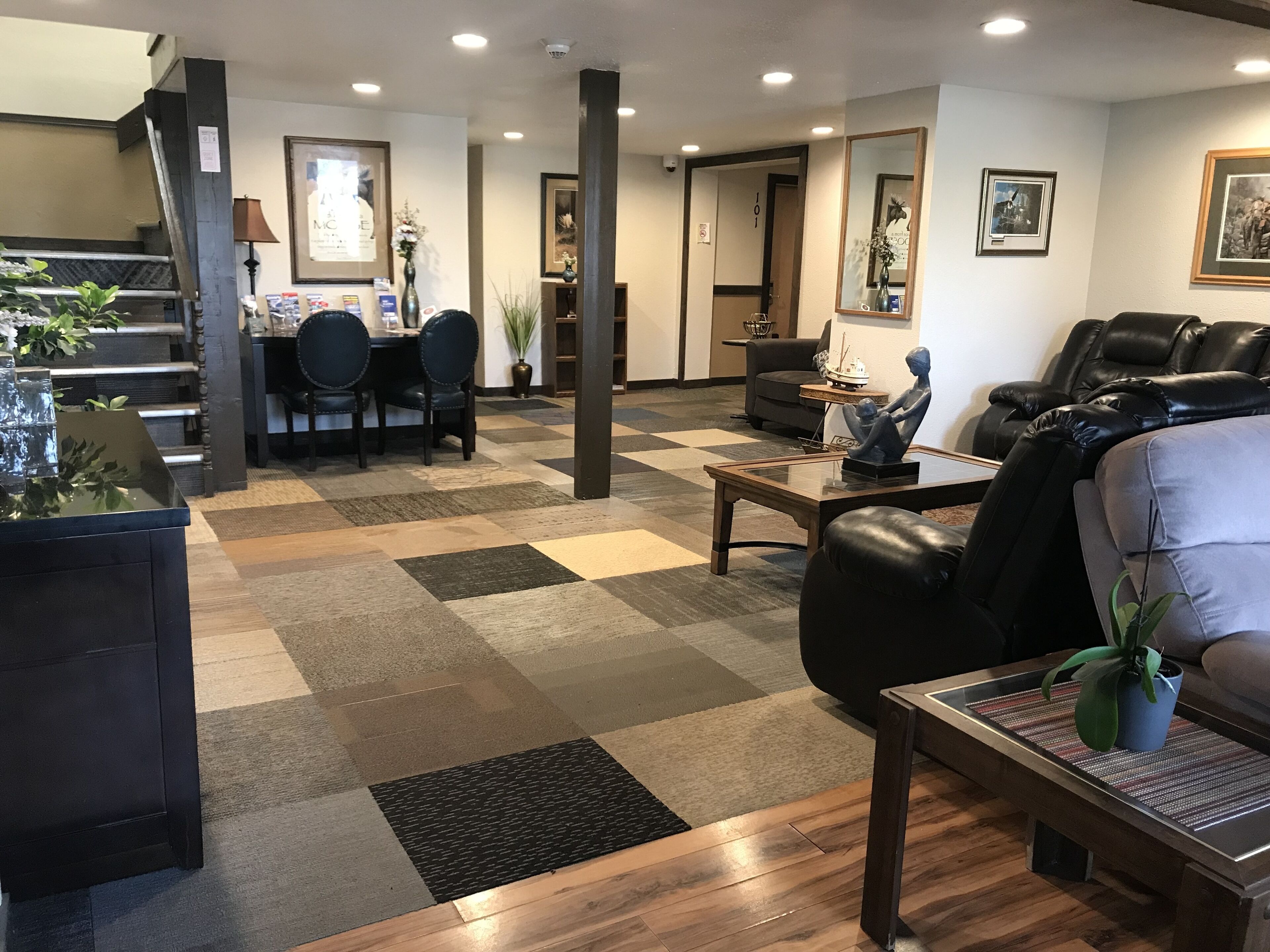 A hotel lobby with a checkered floor, a reception desk, seating area, and a staircase.