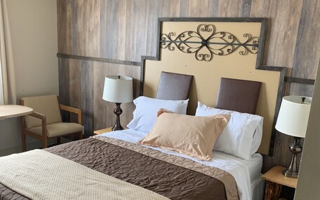 A hotel room with a large bed, two bedside tables with lamps, a chair, and a decorative wall piece.
